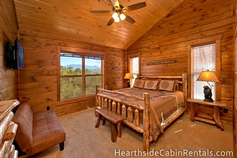 King-size suite inside 8 bedroom Pigeon Forge cabin with wooden furniture, rustic decor and mountain views.