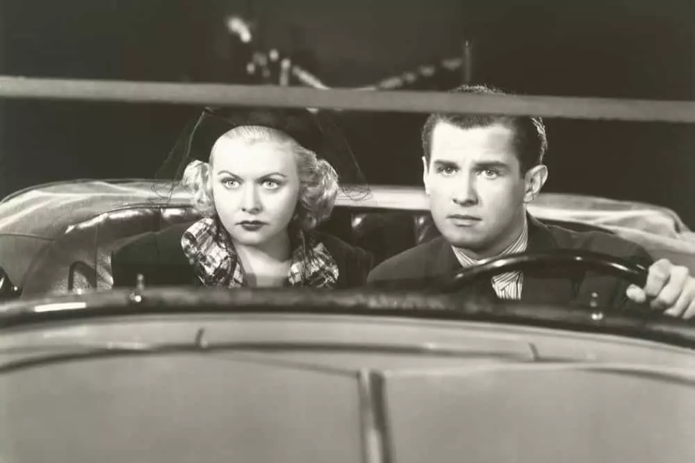 Black and white photo of a couple at a drive-in movie.
