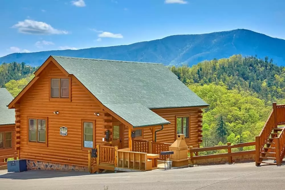 A beautiful log cabin with mountains in the background.