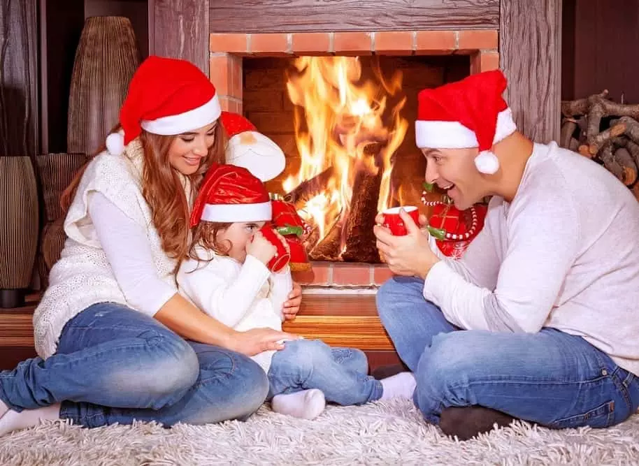 Happy family celebrating Christmas in front of the fireplace in a cabin.
