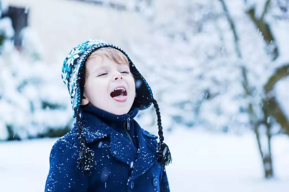 Little boy catching snowflakes on his tongue outside of a three bedroom Pigeon Forge cabin