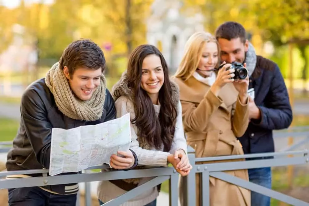 Group of 4 adults, 2 taking a photo and 2 looking at a map