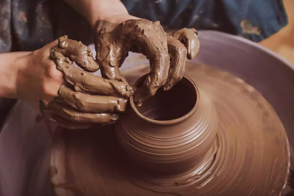 person crafting pottery on wheel