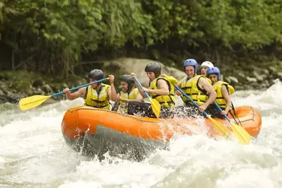 A group of friends whitewater rafting on a river.