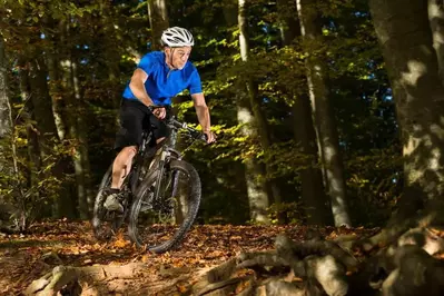 A man mountain biking through the woods.