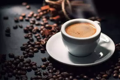 A cup of espresso with coffee beans.