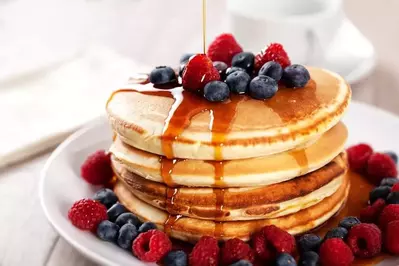 A stack of pancakes covered in berries and syrup.