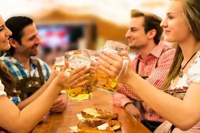 Young people drinking beer and eating pretzels at Oktoberfest.