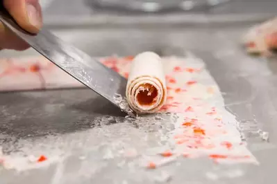 Strawberry flavored ice cream being curled before serving