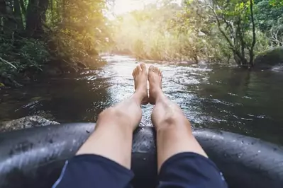 Close up of mans feet while tubing on river in Smoky Mountains.