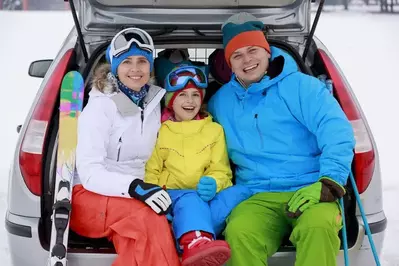 FAmily sitting in the trunk of their car with ski gear