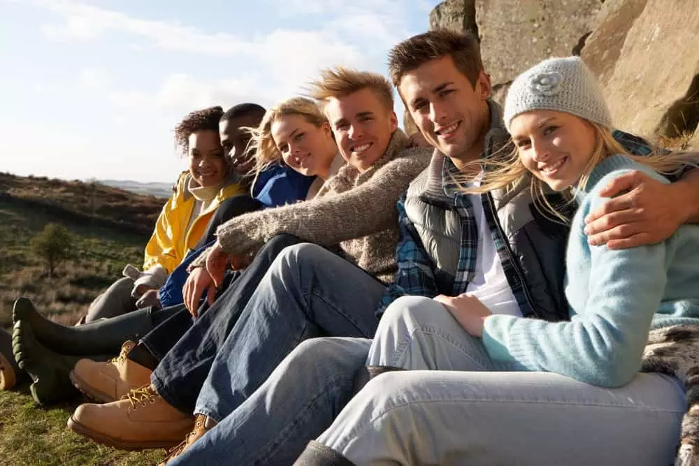 Group of young adults sitting in the countryside while hiking