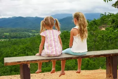 girls sitting on bench looking out at the scenic Smoky Mountains