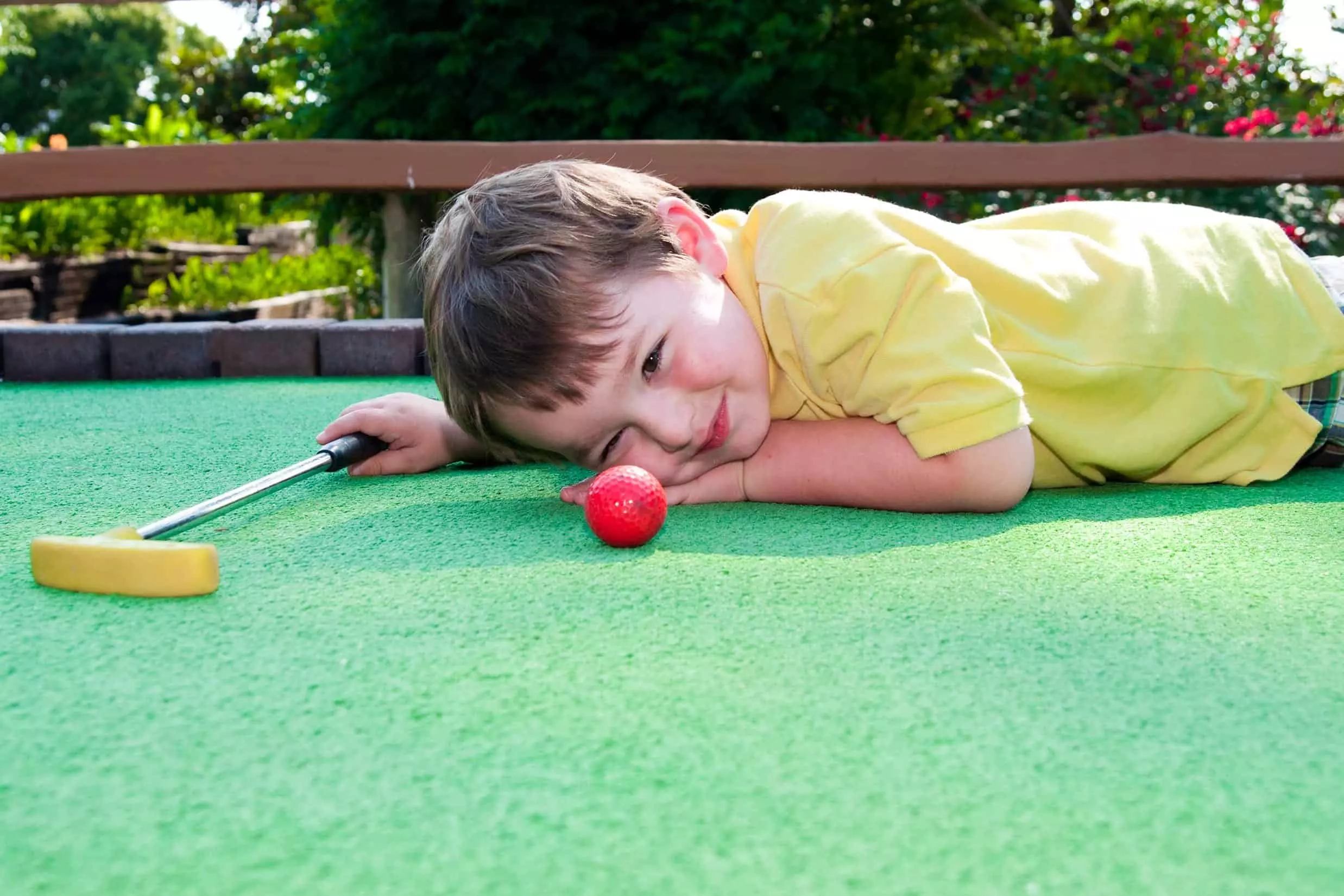 Kid laying on mini golf course