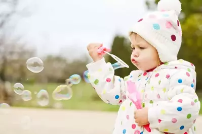 Toddler blowing bubbles in the field