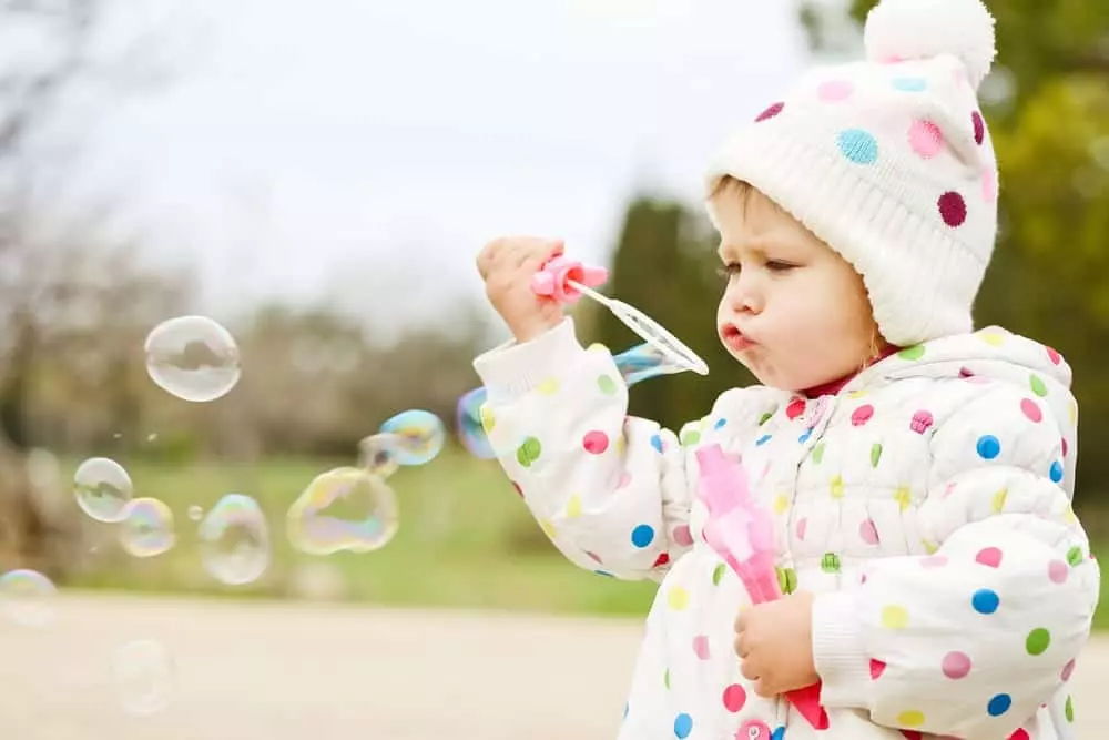 Toddler blowing bubbles in the field
