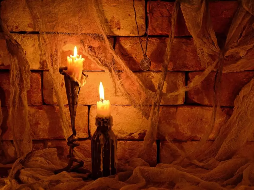 Two candles burning against a brick wall in the dark