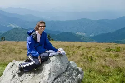 woman on rock in front of mountains