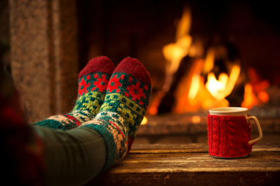 Feet in front of the fireplace with a mug in a cabin.