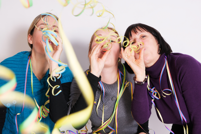 Three women celebrating New Year's Eve with party streamers.