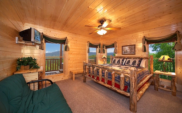  King-size bedroom that overlooks the mountains with tv and full-size futon couch in Majestic View Lodge cabin in Pigeon Forge