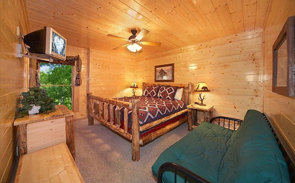 King-size bedroom with tv and full-size futon couch in Majestic View Lodge cabin in Pigeon Forge